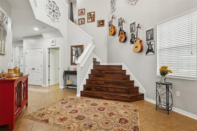 foyer entrance featuring a towering ceiling and light tile patterned floors