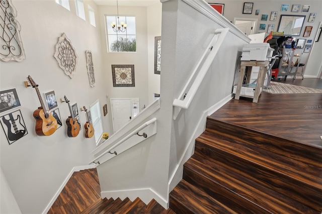 stairs featuring hardwood / wood-style floors, a notable chandelier, and a high ceiling