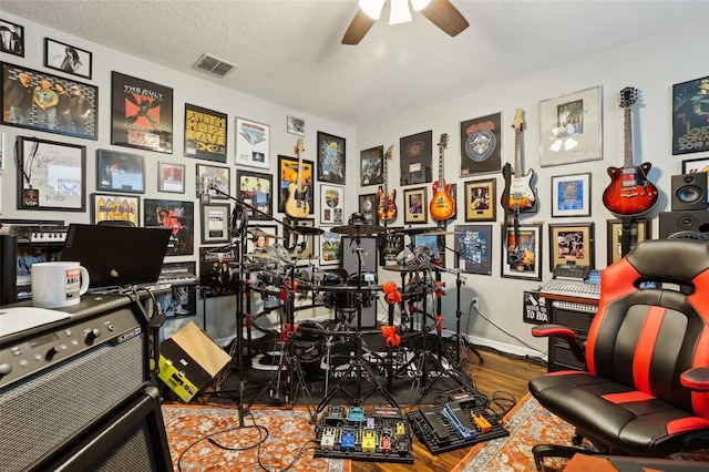 recreation room featuring ceiling fan, wood-type flooring, and a textured ceiling