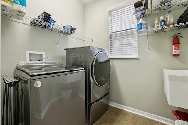 laundry area featuring washer and clothes dryer, tile patterned flooring, and sink