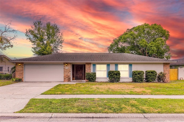 ranch-style house with brick siding, concrete driveway, an attached garage, a front yard, and stucco siding