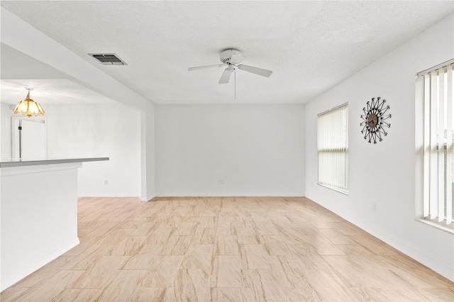 unfurnished room with a healthy amount of sunlight, ceiling fan, and visible vents