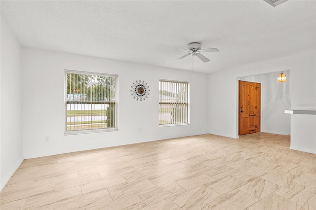 unfurnished room with a textured ceiling, baseboards, and a ceiling fan