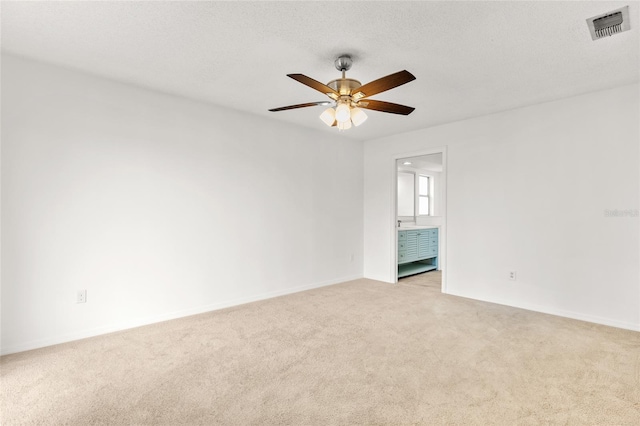 unfurnished room featuring a textured ceiling, visible vents, a ceiling fan, and light colored carpet