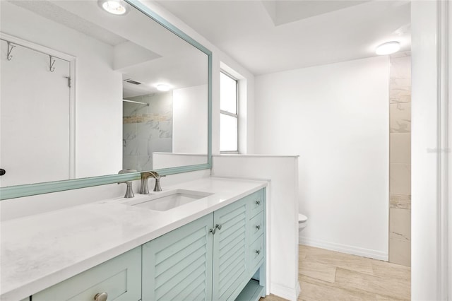 full bath with baseboards, a tile shower, vanity, and toilet