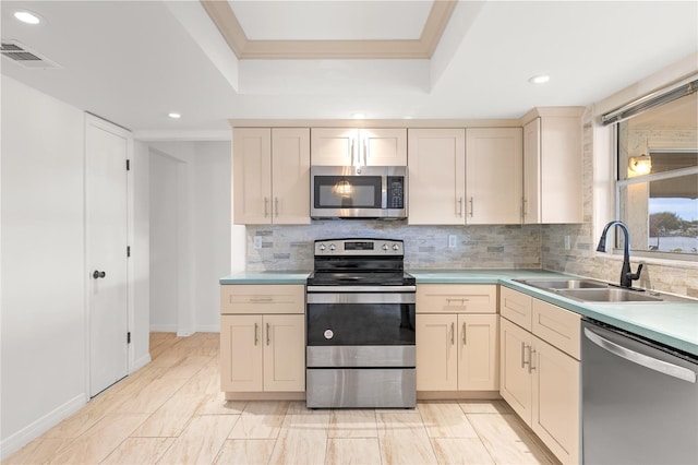 kitchen featuring appliances with stainless steel finishes, cream cabinets, a sink, and visible vents