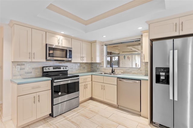 kitchen with tasteful backsplash, a raised ceiling, light countertops, appliances with stainless steel finishes, and a sink