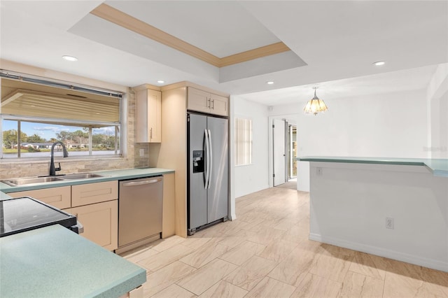 kitchen with a sink, light countertops, appliances with stainless steel finishes, backsplash, and a tray ceiling