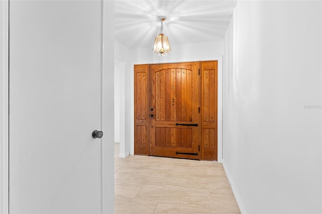 entryway featuring marble finish floor, baseboards, and an inviting chandelier