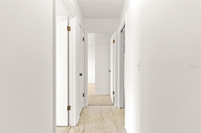 hallway featuring marble finish floor and a textured ceiling