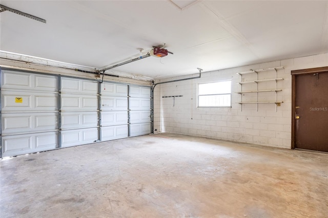 garage featuring concrete block wall and a garage door opener