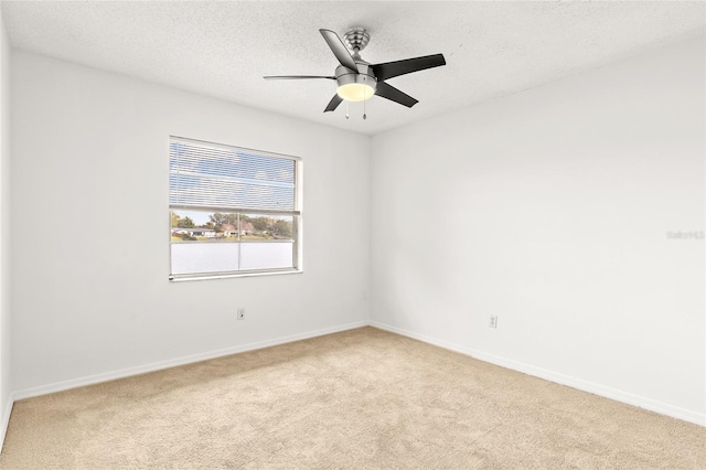 empty room with light carpet, ceiling fan, a textured ceiling, and baseboards