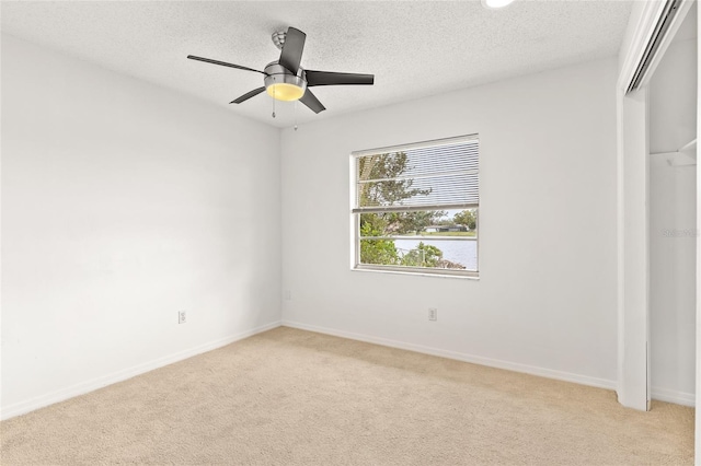 unfurnished bedroom featuring a closet, baseboards, a textured ceiling, and light colored carpet