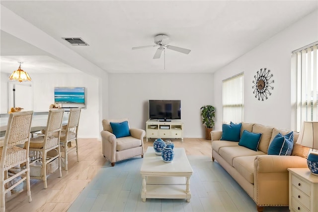 living room featuring baseboards, visible vents, and a ceiling fan