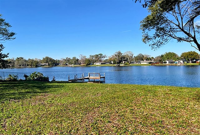 view of dock with a lawn and a water view