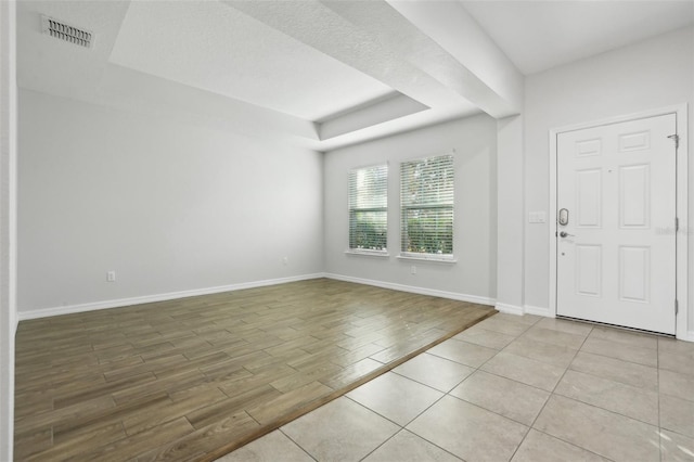 entryway with light tile patterned floors and a tray ceiling