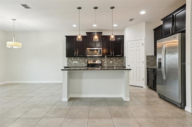 kitchen featuring hanging light fixtures, stainless steel appliances, tasteful backsplash, an island with sink, and light tile patterned flooring