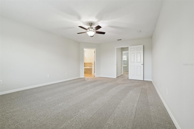 unfurnished bedroom featuring light carpet, a textured ceiling, ensuite bath, and ceiling fan