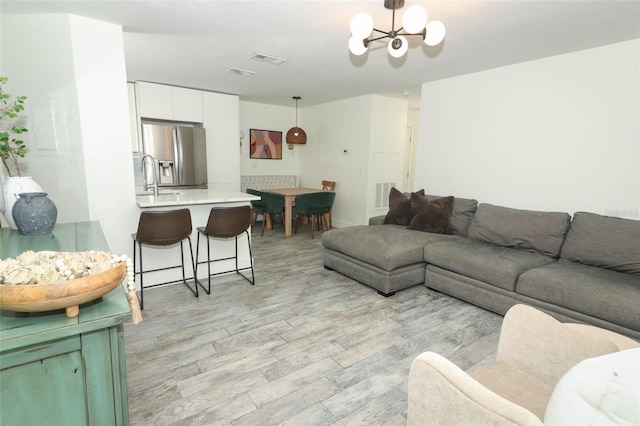 living room with light wood-type flooring, sink, and a chandelier