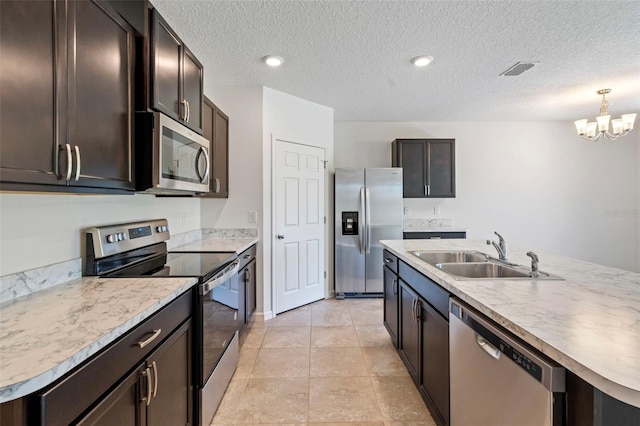 kitchen with sink, stainless steel appliances, an inviting chandelier, an island with sink, and light tile patterned floors