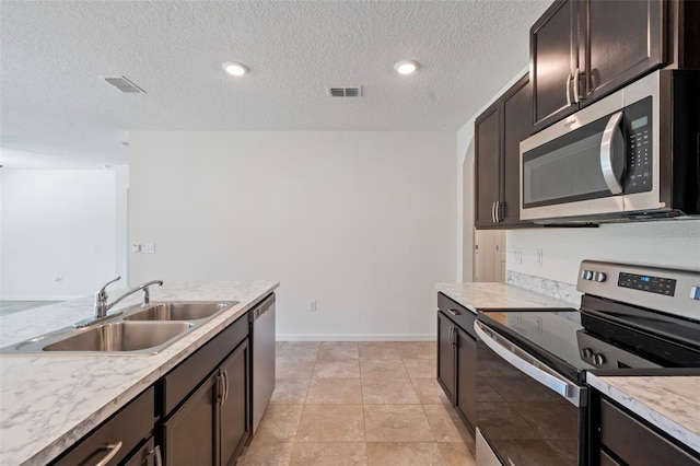 kitchen featuring sink, a textured ceiling, dark brown cabinets, light tile patterned floors, and appliances with stainless steel finishes