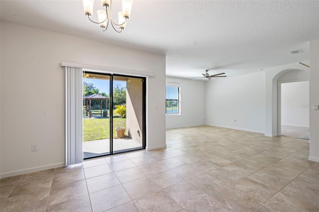 tiled empty room with ceiling fan with notable chandelier, a textured ceiling, and a wealth of natural light