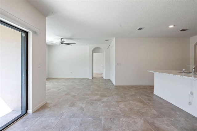 unfurnished room featuring a textured ceiling, ceiling fan, and sink