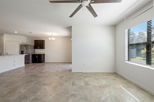 unfurnished living room with ceiling fan with notable chandelier, a healthy amount of sunlight, and sink