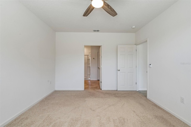 unfurnished bedroom with ceiling fan, light colored carpet, and a textured ceiling