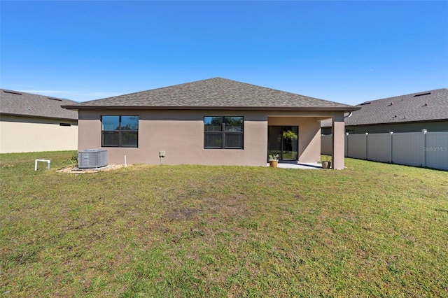 rear view of property featuring a lawn and central AC unit