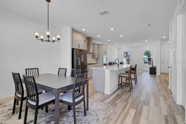 dining space featuring sink, a chandelier, and light hardwood / wood-style floors