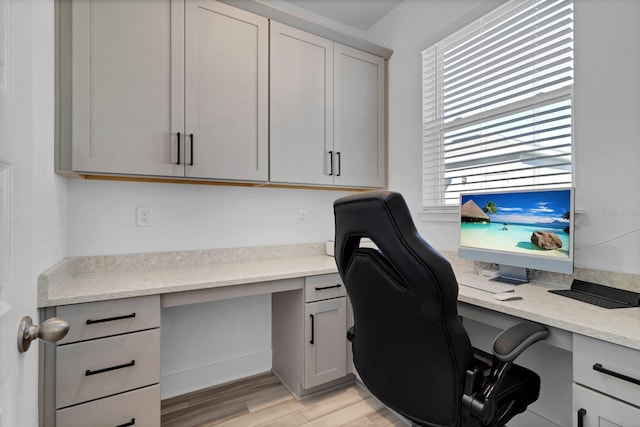 office with built in desk and light wood-type flooring