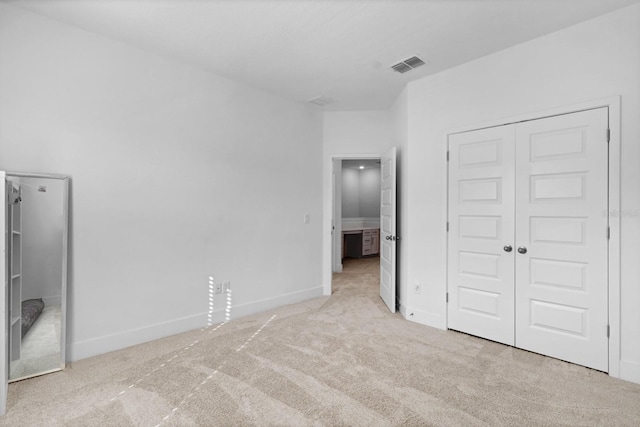 unfurnished bedroom with light colored carpet and a closet