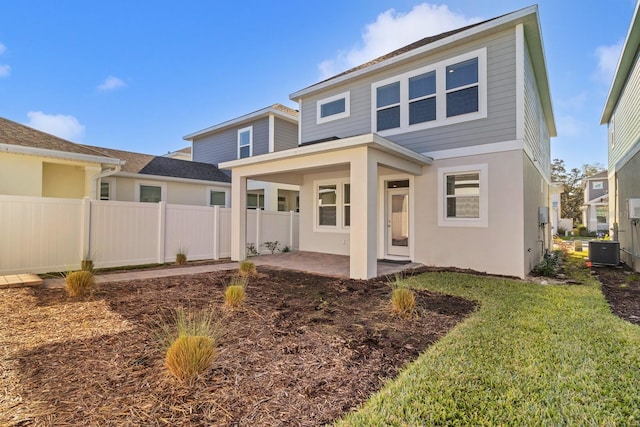 rear view of house featuring a patio, central AC unit, and a yard