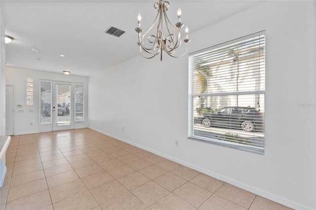 spare room featuring light tile patterned floors and a chandelier