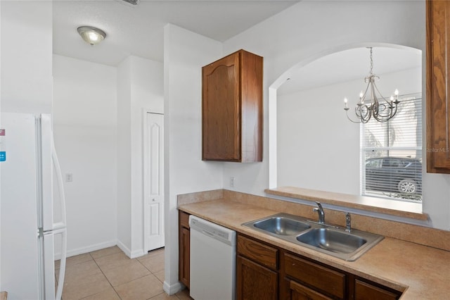 kitchen with pendant lighting, sink, white appliances, light tile patterned floors, and a chandelier