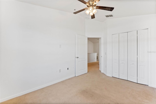 unfurnished bedroom with ceiling fan, light colored carpet, and a closet