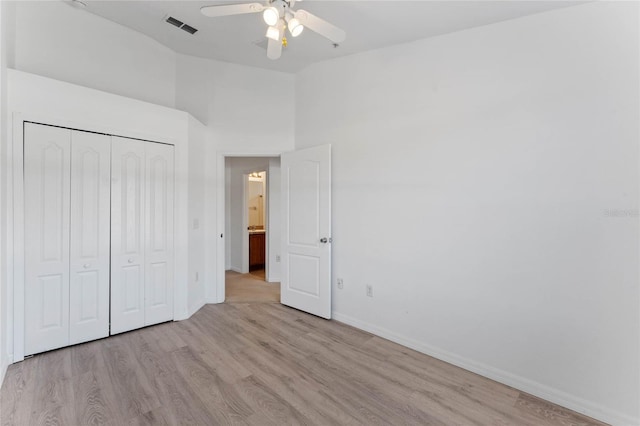 unfurnished bedroom with ceiling fan, lofted ceiling, a closet, and light wood-type flooring