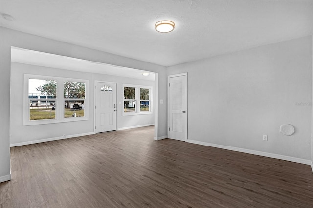 unfurnished room featuring a wealth of natural light and dark wood-type flooring