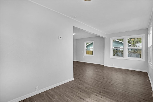 empty room featuring plenty of natural light and dark wood-type flooring