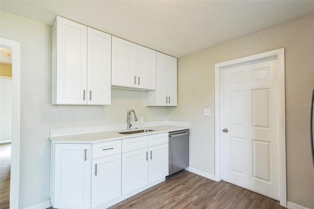 kitchen with stainless steel dishwasher, white cabinetry, sink, and hardwood / wood-style floors