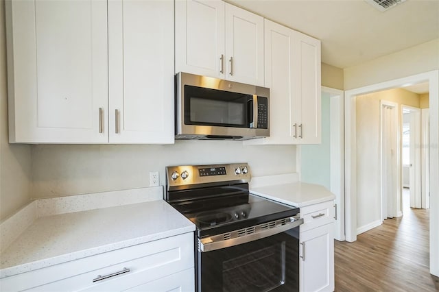 kitchen with white cabinetry, light hardwood / wood-style flooring, light stone counters, and appliances with stainless steel finishes