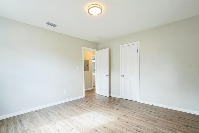 unfurnished bedroom featuring electric panel, light hardwood / wood-style floors, and a closet