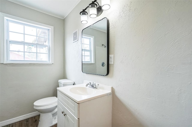 bathroom featuring hardwood / wood-style flooring, vanity, toilet, and ornamental molding