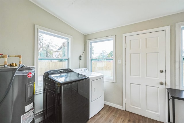 clothes washing area featuring washer and dryer, electric water heater, and light hardwood / wood-style flooring