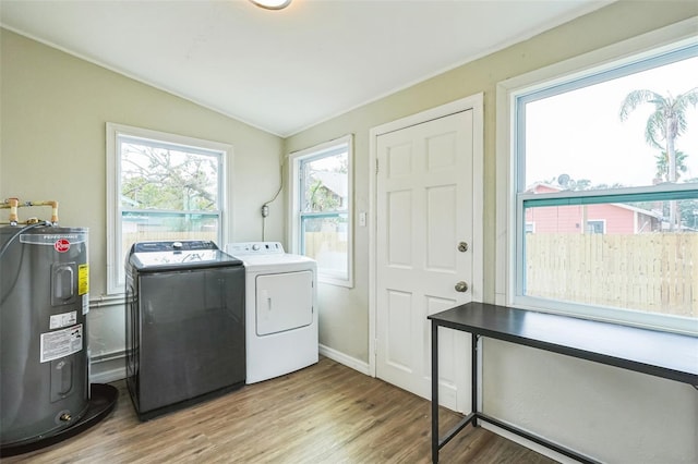 washroom featuring washing machine and dryer, water heater, plenty of natural light, and light hardwood / wood-style floors