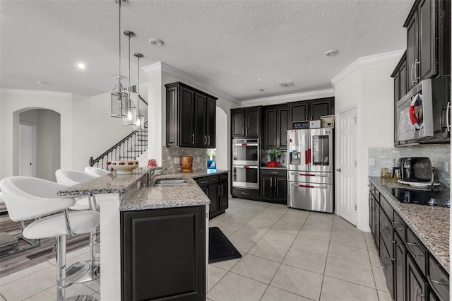 kitchen with backsplash, a kitchen breakfast bar, light tile patterned floors, decorative light fixtures, and stainless steel appliances