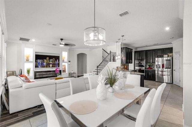 tiled dining space with ceiling fan and ornamental molding