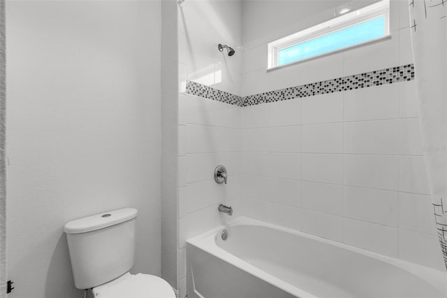 bathroom featuring tiled shower / bath combo and toilet