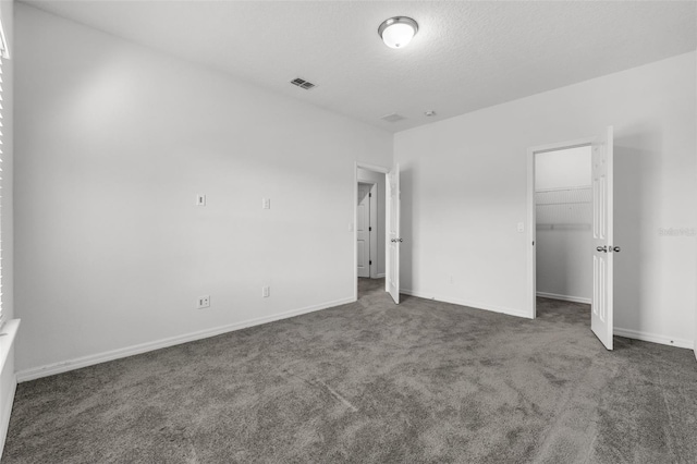 unfurnished bedroom featuring a closet, dark carpet, and a textured ceiling